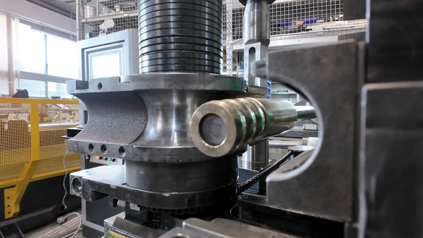 Piegatrice al lavoro su un tubo di acciaio inox a parete spessa.